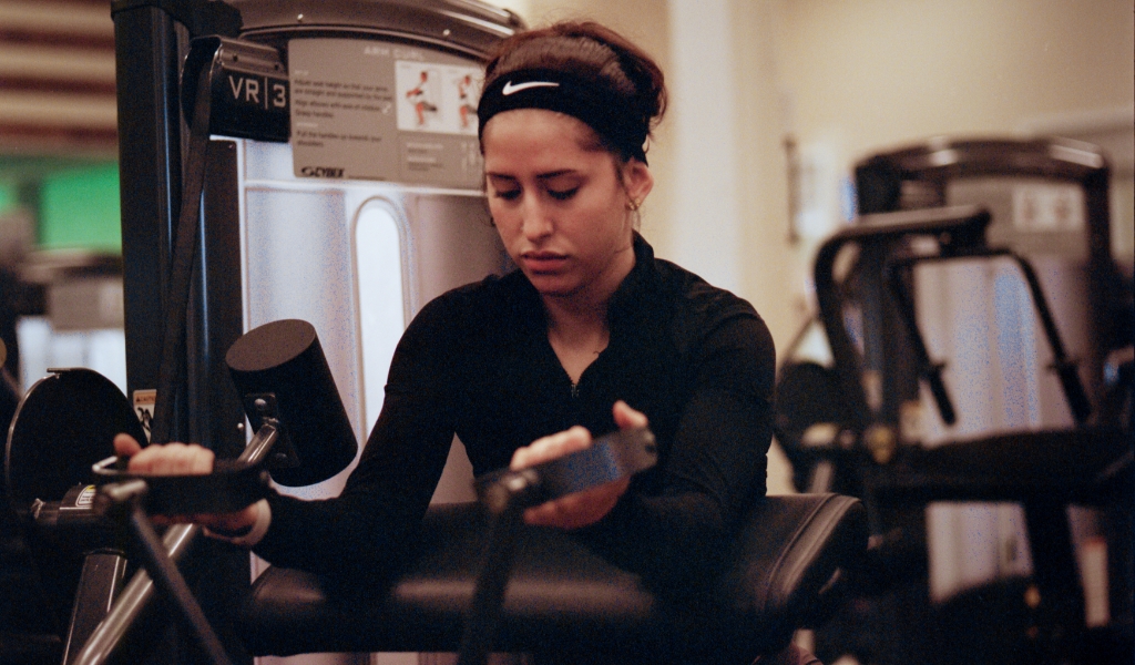 young woman using a curl station to workout at the body kinetics gym in san rafael