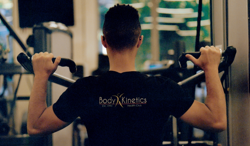 man in a body kinetics shirt using arm equipment to workout at the body kinetics gym in san rafael